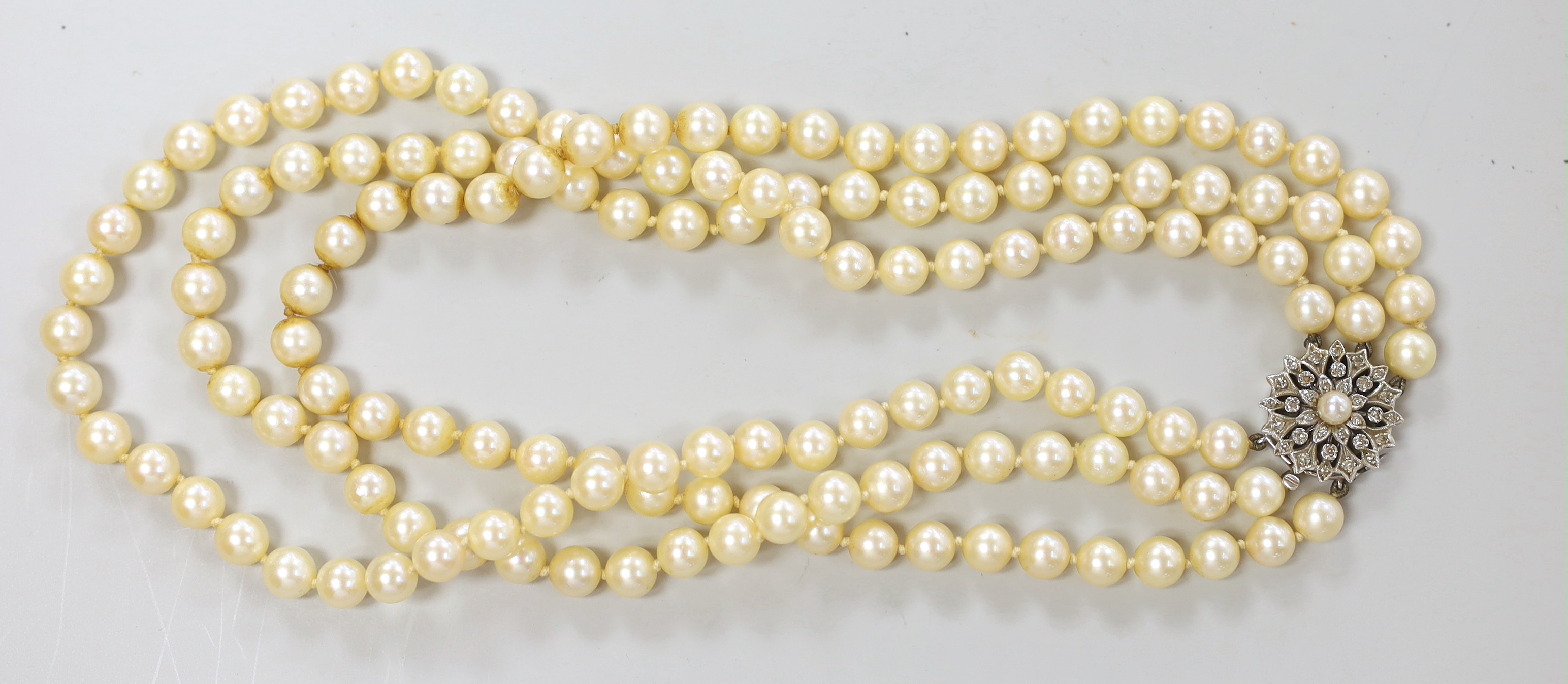 A 1960's triple strand cultured pearl choker necklace, with diamond and cultured pearl cluster set white metal clasp, 40cm, with box and 1968 original purchase receipt.